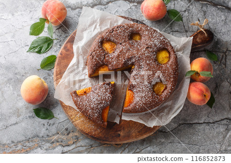 Fruit chocolate peach sponge cake summer dessert close-up on wooden board. Horizontal top view 116852873