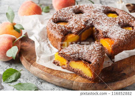 Delicious cocoa peach brownie or chocolate peach sponge cake closeup on wooden board. Horizontal Delicious cocoa peach brownie or chocolate peach sponge cake closeup on wooden board. Horizontal 116852882