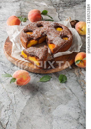 Chocolate fruit pie sponge cake filled with peaches close-up on wooden board. Vertical Chocolate fruit pie sponge cake filled with peaches close-up on wooden board. Vertical 116852884