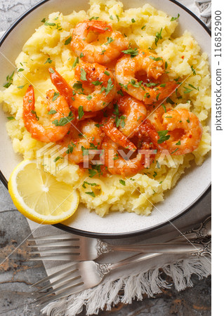 Lemon garlic shrimps with mashed potatoes and herbs close-up in a bowl on the table. Vertical top view 116852900