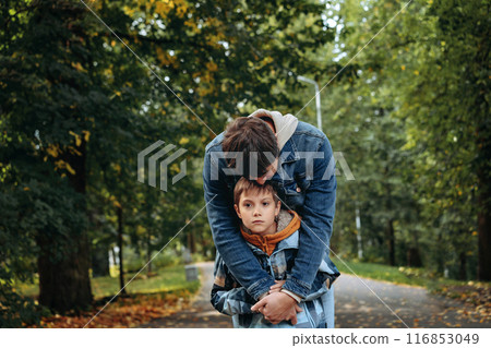 Caucasian man hugging his son in autumn park supporting sad boy 116853049