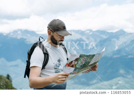 tourist man hiking in mountains looking at the map for direction tourist man hiking in mountains looking at the map for direction 116853055