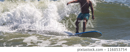 Man surfing with a wall of water of a breaking wave behind him 116853754