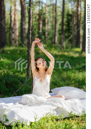 Girl wakes up in a summer forest Girl wakes up in a summer forest 116855247