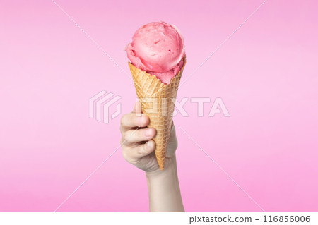 Woman's hand holding waffle cone with strawberry ice cream on pink background Woman's hand holding waffle cone with strawberry ice cream on pink background 116856006