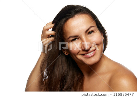 Close up photo of beautiful woman with long, brunette hair posing looking at camera against white studio background. 116856477