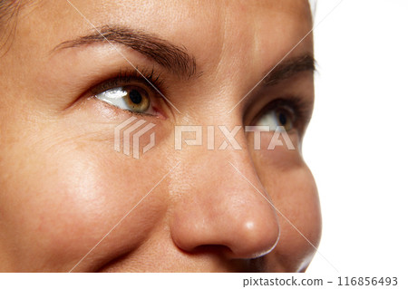 Detailed photo of woman's face, preorbital zone with well-kept, smooth skin against white studio background. Anti-aging skincare cosmetic products. Detailed photo of woman's face, preorbital zone with well-kept, smooth skin against white studio background. Anti-aging skincare cosmetic products. 116856493