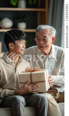 A son gives his father a gift, beautifully packaged in a box. Strong family ties 116858062