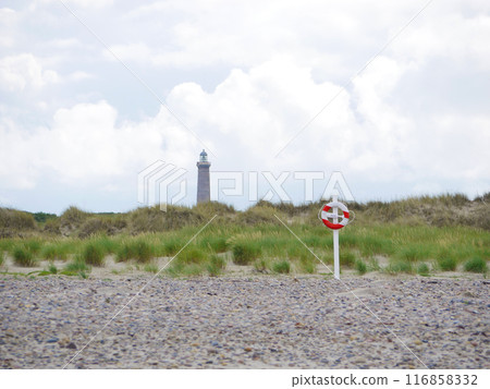 Red and white lifebuoy on the beach in Skagen, Denmark at the background of a lighthouse. Life saving rescue buoy. Lifeguard preserving concept Red and white lifebuoy on the beach in Skagen, Denmark at the background of a lighthouse. Life saving rescue buoy. Lifeguard preserving concept 116858332