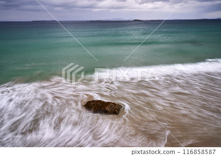 long exposure beach waves around rock cloudy day long exposure beach waves around rock cloudy day 116858587
