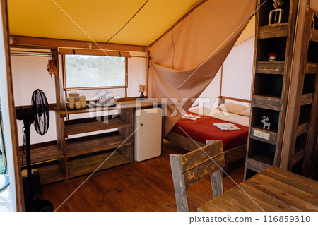 Interior of cozy open glamping tent. Camping tent for outdoor summer holiday and vacation Interior of cozy open glamping tent. Camping tent for outdoor summer holiday and vacation 116859310