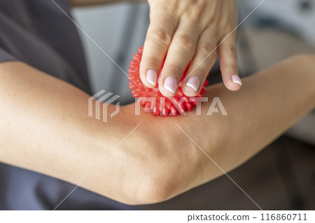 Shot of the female doctor manual therapist holding portable massage ball, Showing how to apply pressure with it 116860711