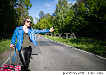 A teenager is standing with a pink suitcase on wheels and tries to stop the opportunity to go on vacation faster. A teenager is standing with a pink suitcase on wheels and tries to stop the opportunity to go on vacation faster. 116861367