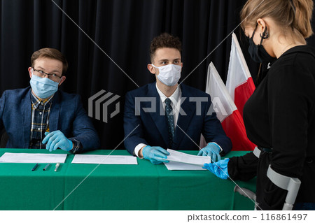 A teenager throws a completed electoral card into the transparent ballot box. 116861497
