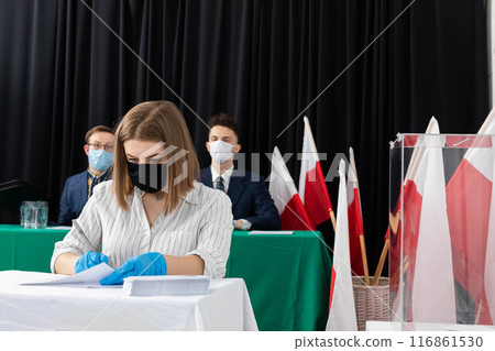 A teenager entitled to vote sits at a polling station and fills out a ballot paper for the President of Poland. 116861530