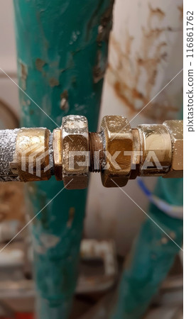 Close-up of rusty pipe connections with brass fittings, showcasing wear and tear in plumbing systems. 116861762