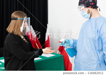 A woman from an election commission disinfects her hands before sitting at an election table. 116862011