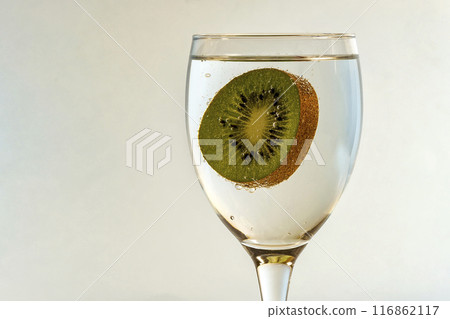 Kiwi covered with bubbles of gas in a glass on a light blurred background Kiwi covered with bubbles of gas in a glass on a light blurred background 116862117