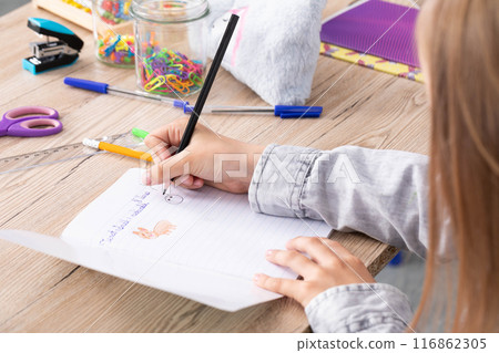 The student draws with crayons in the teddy bear school notebook as the subject of today's lesson. 116862305