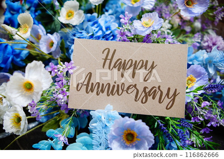 Happy Anniversary text write on paper card with flowers decoration on wooden background Happy Anniversary text write on paper card with flowers decoration on wooden background 116862666