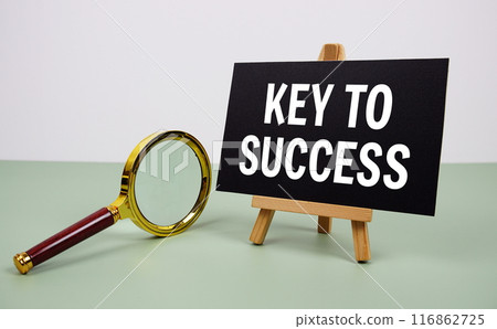 Key to Success text on paper card with magnifying glass on green background 116862725