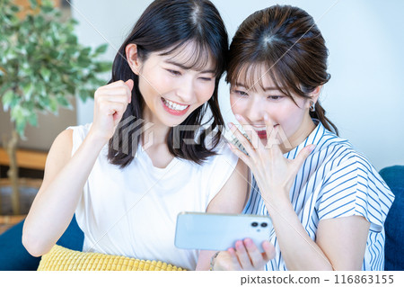 Two women enjoying videos on a smartphone Two women enjoying videos on a smartphone 116863155