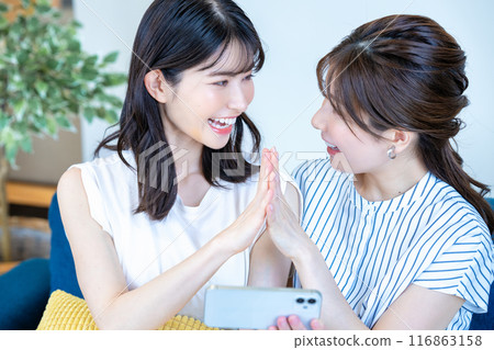 Two women enjoying videos on a smartphone 116863158