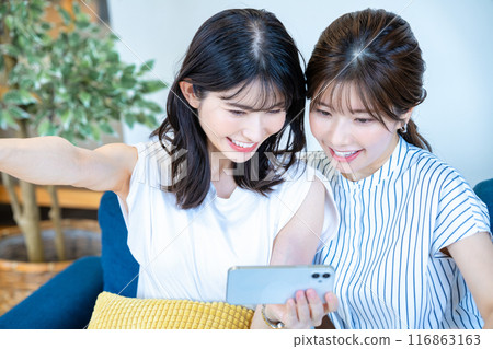 Two women enjoying videos on a smartphone Two women enjoying videos on a smartphone 116863163