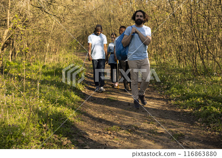 Motivated team of volunteers finishing garbage cleaning mission cleanup in the woods, grabbing their disposal bags and going home. Satisfied people volunteering to clean the ecosystem. Motivated team of volunteers finishing garbage cleaning mission cleanup in the woods, grabbing their disposal bags and going home. Satisfied people volunteering to clean the ecosystem. 116863880