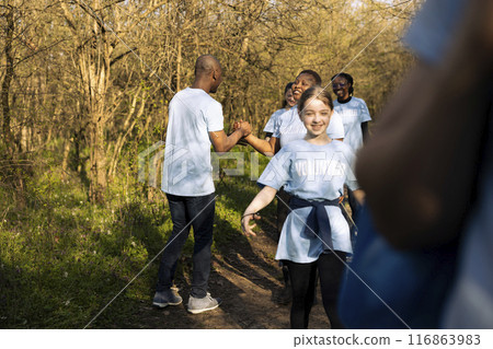 Male environmentalist sharing a high five with all of his team, enjoying successful mission to protect the natural ecosystem. African american activist being happy with a job well done. 116863983