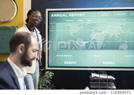 Employee presenting capital funds and revenue data on annual statistics in a meeting room, reviewing capital increase and budget allocation for a project. Informative conference in a boardroom. Employee presenting capital funds and revenue data on annual statistics in a meeting room, reviewing capital increase and budget allocation for a project. Informative conference in a boardroom. 116864071