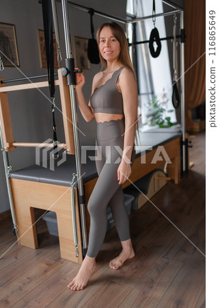 Pilates fitness trainer in pilates studio. Young sporty attractive woman wearing sportswear in yoga studio. Fit, healthy and strong authentical body. Fitness concept 116865649