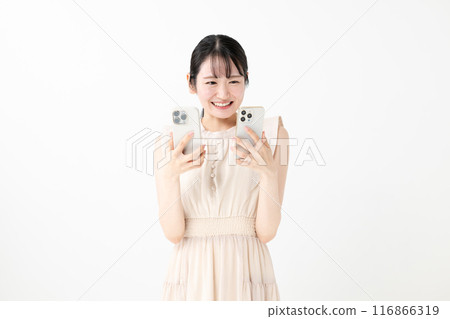 A smiling woman holding two smartphones 116866319