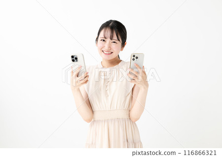 A smiling woman holding two smartphones 116866321