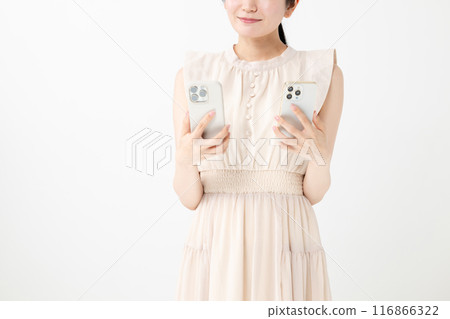 A smiling woman holding two smartphones 116866322