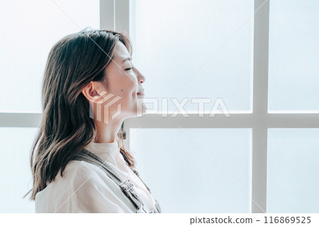 Profile of a young woman by the window 116869525