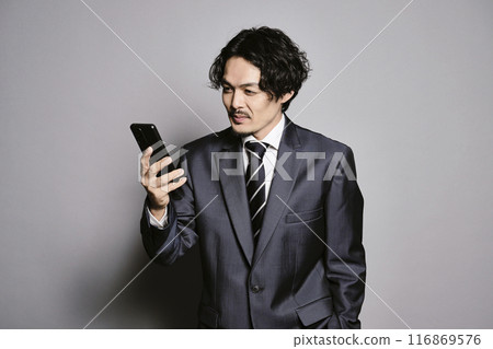 A man looking at his smartphone on a gray background A man looking at his smartphone on a gray background 116869576