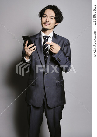 一個男人在灰色背景下看著智慧型手機 116869612