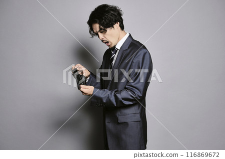 Man holding an empty wallet on a grey background 116869672