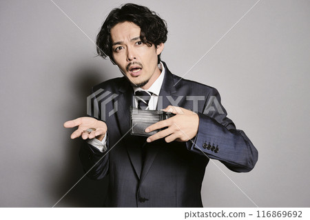 Man holding an empty wallet on a grey background Man holding an empty wallet on a grey background 116869692