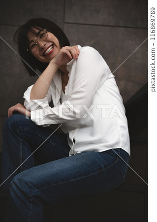Casual young woman with glasses relaxing on the stairs 116869789