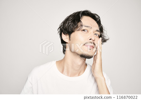 A man holding his hand on his cheek against a white background A man holding his hand on his cheek against a white background 116870022