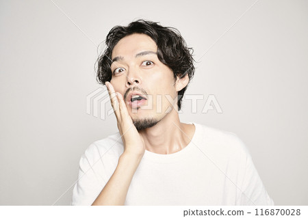 A man holding his hand on his cheek against a white background 116870028