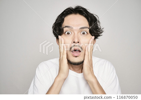 A man holding his hand on his cheek against a white background 116870050