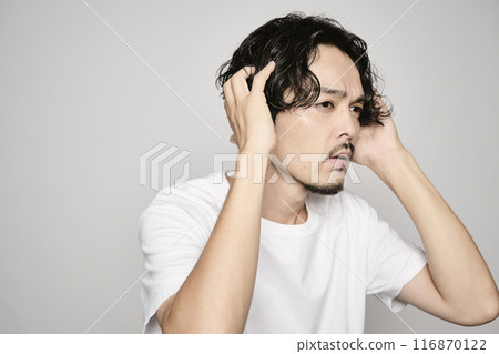 一個男人在白色背景下撫摸他的頭髮 一個男人在白色背景下撫摸他的頭髮 116870122