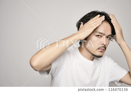 A man touching his hair on a white background 116870136