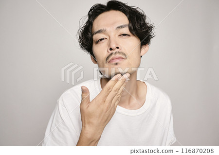 A man holding his hand on his cheek against a white background 116870208