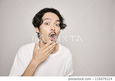 A man holding his hand on his cheek against a white background A man holding his hand on his cheek against a white background 116870224