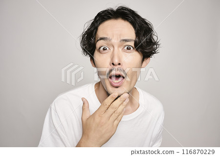 A man holding his hand on his cheek against a white background 116870229
