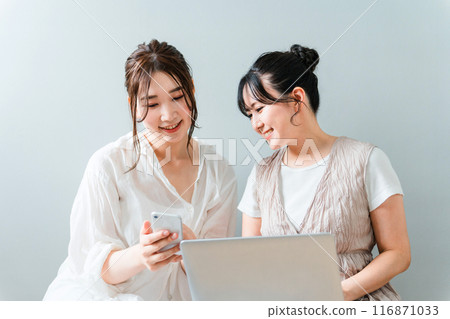 在家中同時使用智慧型手機和筆記型電腦的女性、朋友、媽媽朋友和同事 在家中同時使用智慧型手機和筆記型電腦的女性、朋友、媽媽朋友和同事 116871033